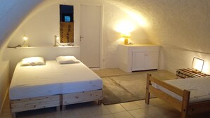 Ein gemütliches Schlafzimmer unter dem Dach mit einem Einzelbett, einem kleinen Schreibtisch und einem Sessel.