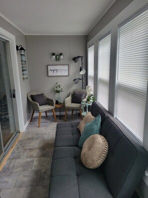 Una sala moderna con un sofá gris, sillas de mimbre y una mesita con plantas.