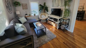 Un salon moderne avec un canapé, une table basse, un téléviseur et un ventilateur de plafond.