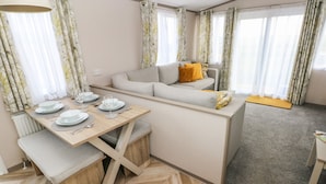 Ett kompakt bostadsutrymme med en matplats, soffa och ett litet pentry.