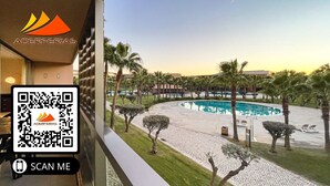 A hotel with a pool surrounded by palm trees and a clear sky. - Herdade dos Salgados, T3 8C-1B, Vila das Lagoas (Albufeira)