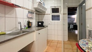 Une cuisine avec des carreaux blancs, un évier, un plan de travail et une fenêtre.