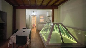 Un espace repas comprenant une table et des chaises, une vitrine et une porte donnant sur une autre pièce.