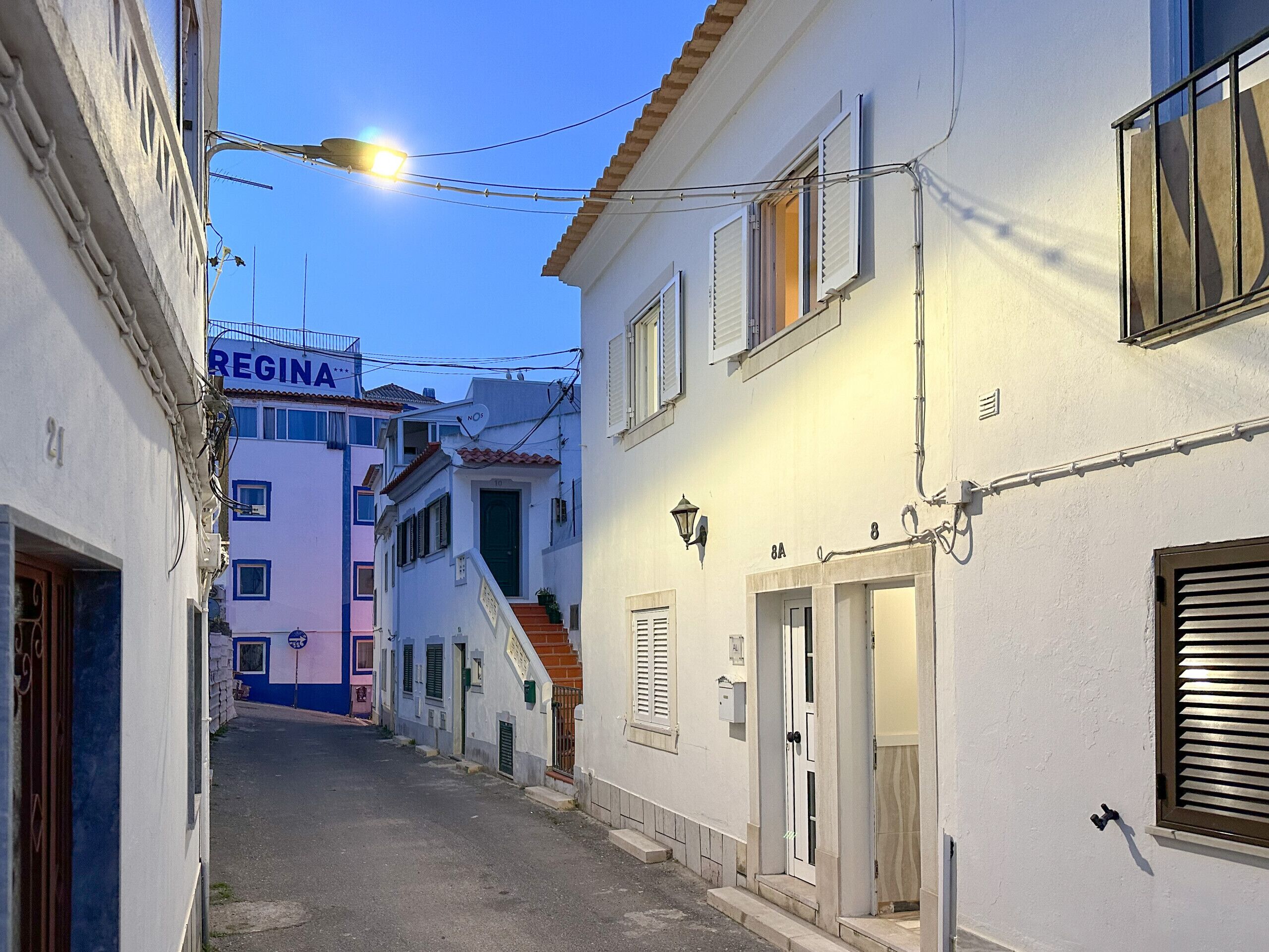 A narrow street with buildings on either side, a visible street lamp, and a sign reading "REGINA".