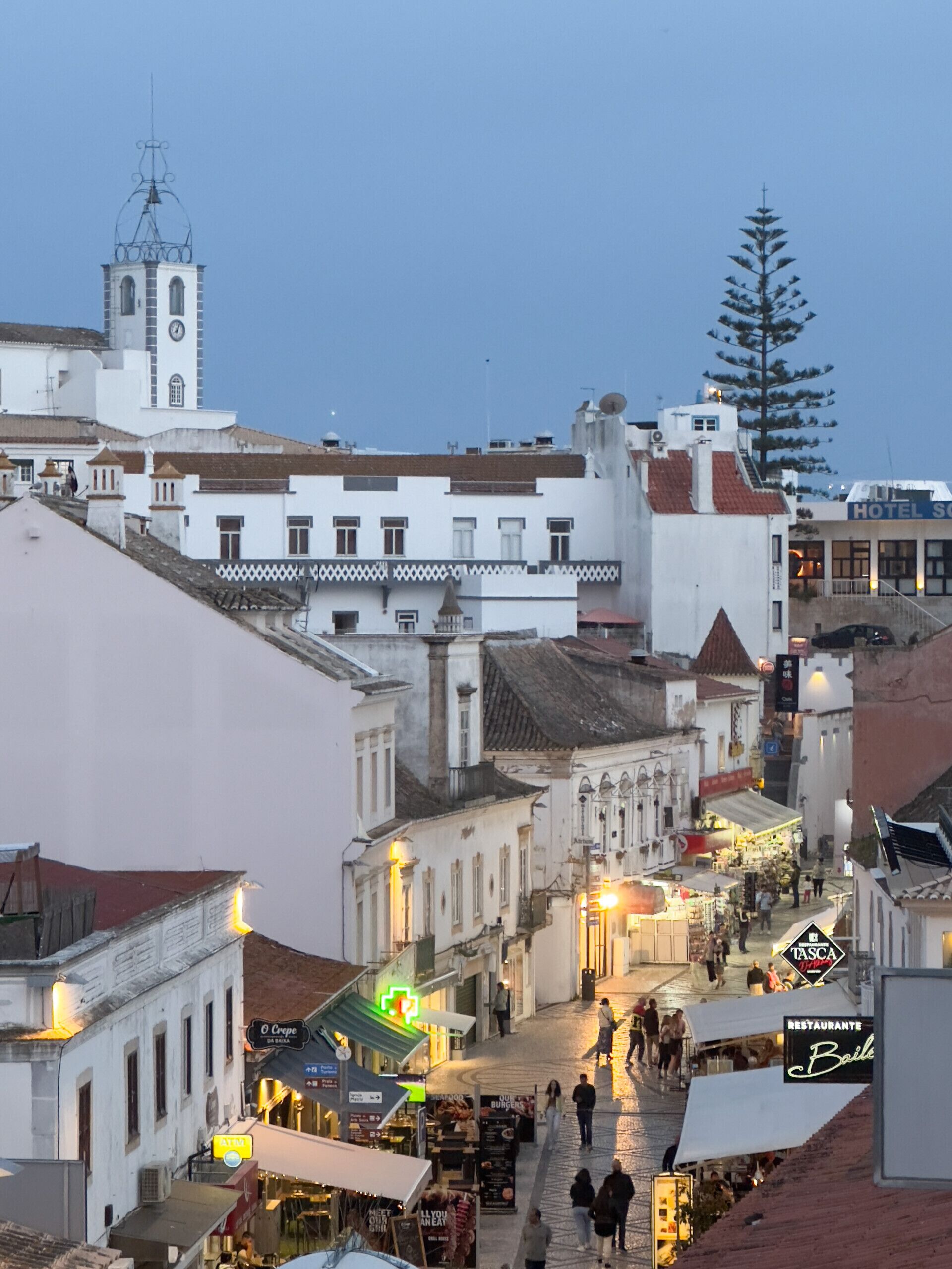 A historic town square with traditional architecture, a clock tower, and a variety of shops and restaurants.