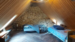 Ein gemütliches Schlafzimmer im Dachgeschoss mit schrägen Wänden, Steinmauer und Holzbalken.