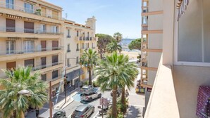 A multi-story building with balconies, palm trees, and a street view. - Le Neptune by Interhome (Sainte Maxime)
