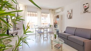A modern living room with a glass coffee table, grey sofa, and a dining area with chairs and a table. - Le Neptune by Interhome (Sainte Maxime)