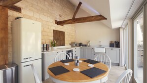 A kitchen with a white refrigerator, wooden dining table, and white chairs. - Luxury 2-Bed Cotswolds Barn with Private Hot Tub | Sleeps 4 (Gloucester)
