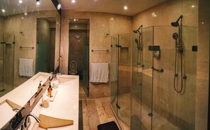 Un baño moderno con un espejo grande, un tocador con lavabo y una zona de ducha con mampara de vidrio.