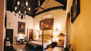 Ein traditionell eingerichtetes Schlafzimmer mit Himmelbett, einer Kristallleuchter und einem großen Gemälde an der Wand.