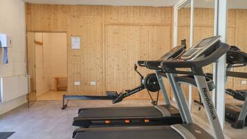 A gym with treadmills, a wooden wall, a mirror, and a small bench.