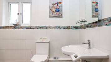 Une salle de bain moderne équipée de toilettes, d’un lavabo et d’un revêtement mural décoratif en carreaux.