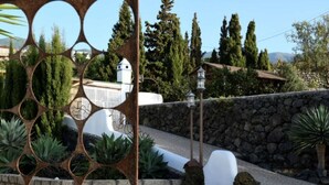 A stone wall, a white building, and a metal fence with circular cutouts. - Casa Saskia with view to Avocado plantation and Atlantic.
Heated Poolarea (La Matanza de Acentejo)