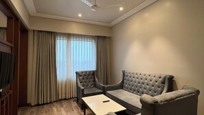 A modern living room with a sofa, two armchairs, a coffee table, and a ceiling fan. - Hotel Apricia  (Ludhiana)