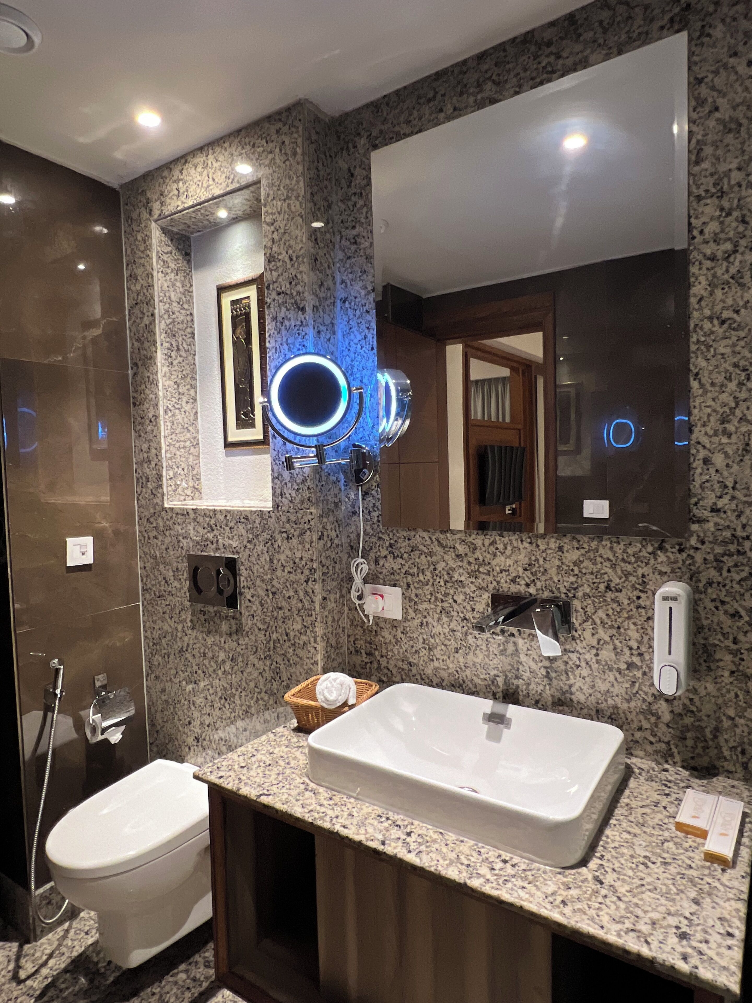 A modern bathroom with a granite countertop, a white sink, and a large mirror.