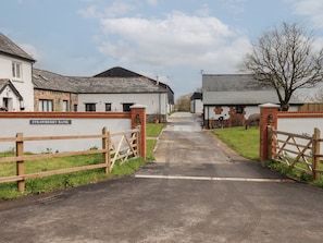 A rural road leading to a row of white buildings with a sign reading "STRAWBERRY BANK".