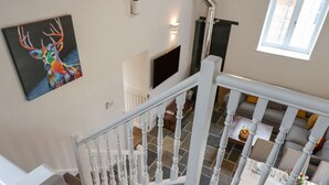 A staircase with white balusters leading to a dining area with a table set for four. - Strawberry Bank - Pipistrelle (Holsworthy)