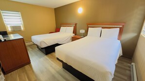 Ein Hotelzimmer mit zwei Betten, einem Schreibtisch und einem Fenster mit Jalousien.