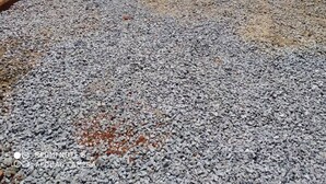 A gravel courtyard with a metal gate, a brick wall, and a concrete building. - Apartment, Bairro Santa Lúcia, covered garage 2.50x4.70 (Montes Claros)