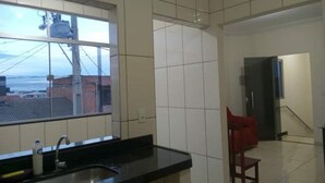 A kitchen with a window, a sink, and a red chair. - Apartment, Bairro Santa Lúcia, covered garage 2.50x4.70 (Montes Claros)