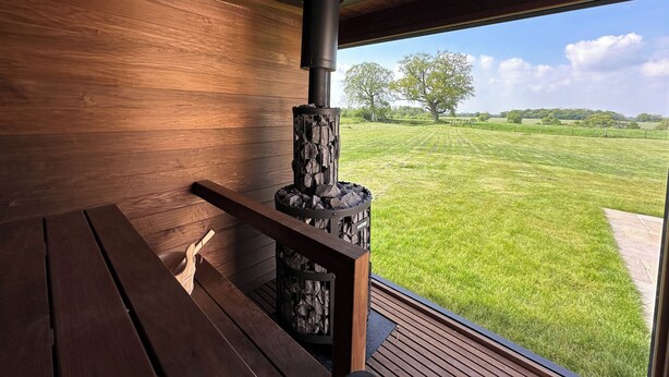 Un intérieur en bois donnant sur un champ verdoyant et des arbres.