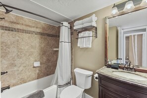 Un baño con ducha, inodoro, lavamanos y espejo.