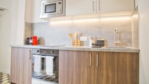 A modern kitchen with wooden cabinets, a built-in microwave, and a stainless steel oven. - Trendy familly apt in Mouffetard (Paris)