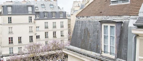 Une cour bordée de bâtiments, un arbre en fleurs et des gens.