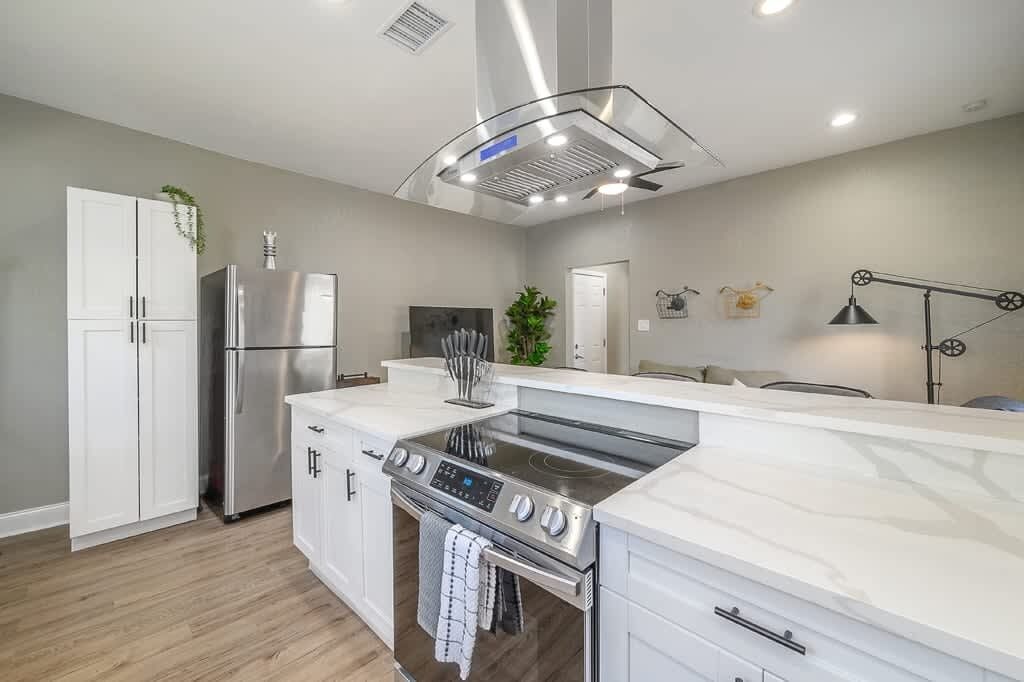 A modern kitchen with white cabinets, stainless steel appliances, and a central island.