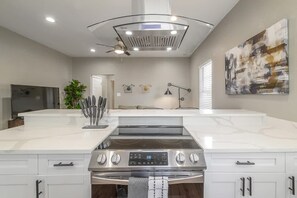 Eine moderne Küche mit einer großen Kochinsel, Edelstahlgeräten und einem Deckenventilator.