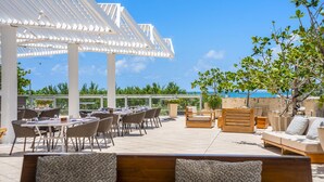 Eine Terrasse im Freien mit Tischen und Stühlen, einer Holzbank und einer Pergola.