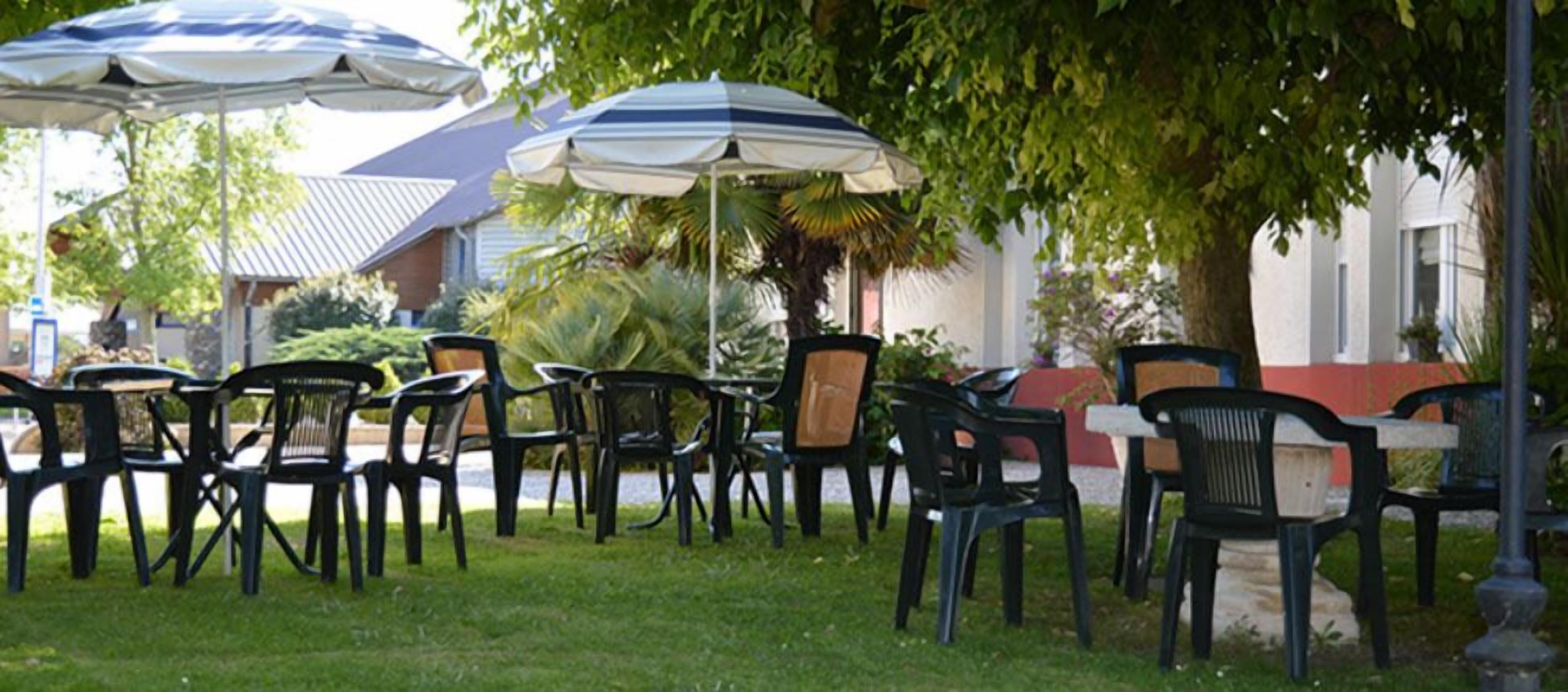 Outdoor seating with umbrellas and chairs arranged on grass.