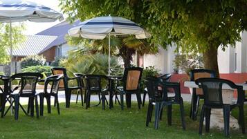 Outdoor seating with umbrellas and chairs arranged on grass.