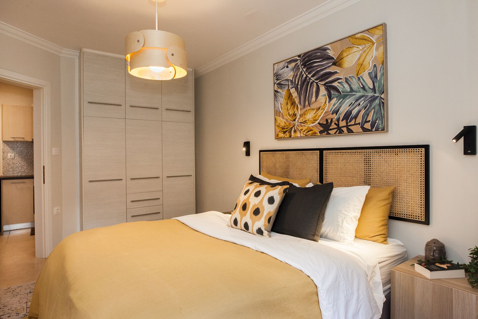 A bedroom with a bed, a wardrobe, a painting, and a bedside table.