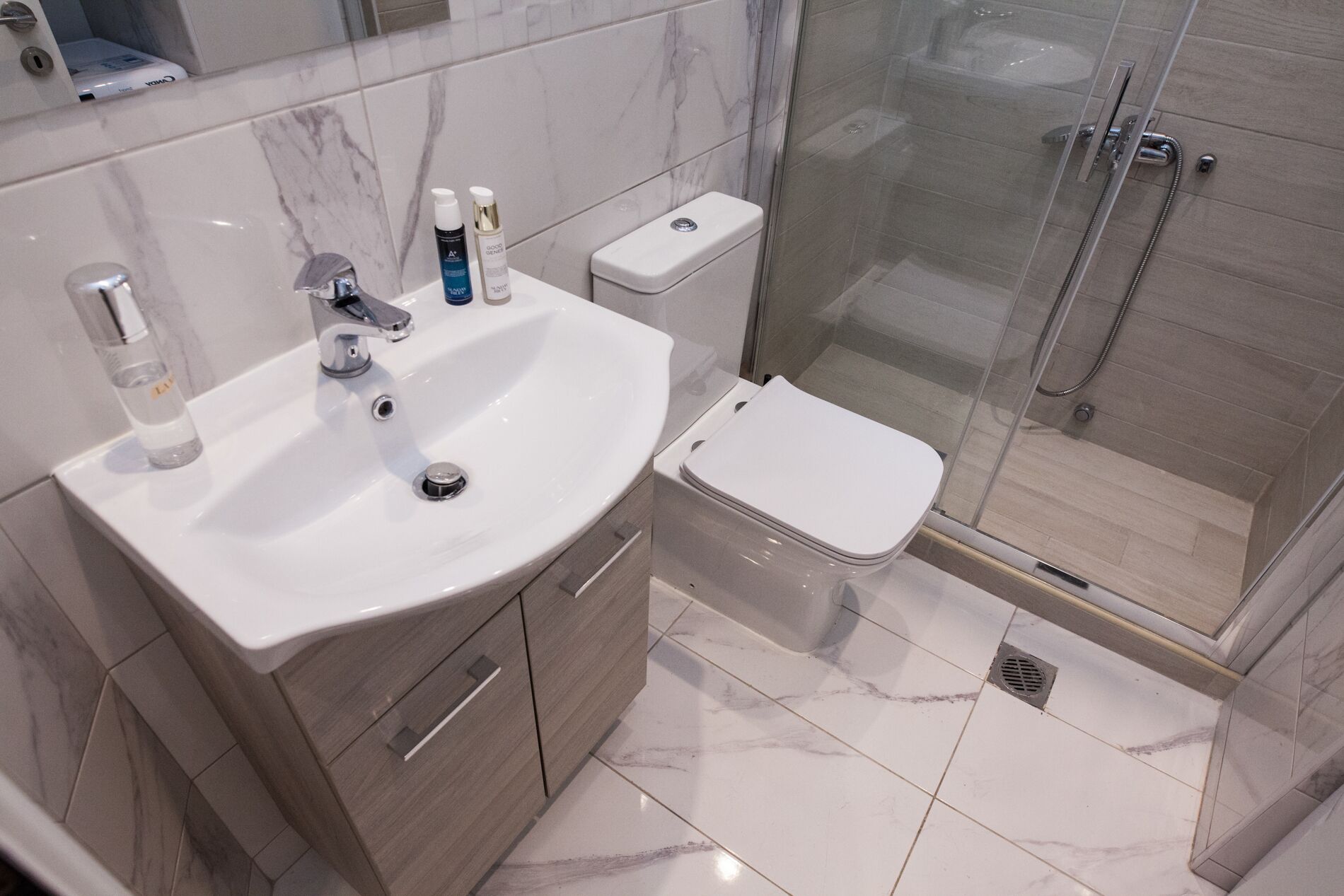 A modern bathroom with a white sink, a toilet, and a glass-enclosed shower area.