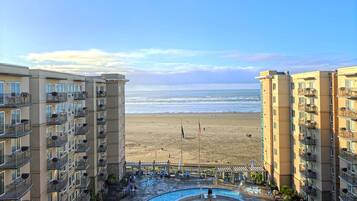 Un hotel frente a la playa con varios balcones, piscina y vistas al océano.