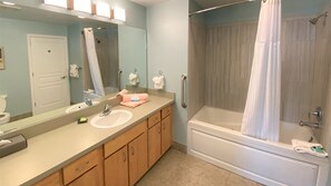 A bathroom with a sink, mirror, vanity, shower, and toilet.
