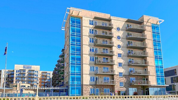 A multi-story hotel with balconies, a beachside location, and a clear blue sky. - Seaside Resort - Deluxe 2 Bedroom 2 Bath - Assignment 1 (Seaside)