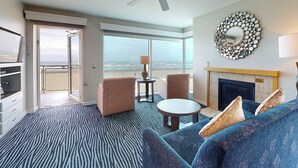 Een hotelkamer met een groot raam, een bank, een kleine tafel en een open haard.