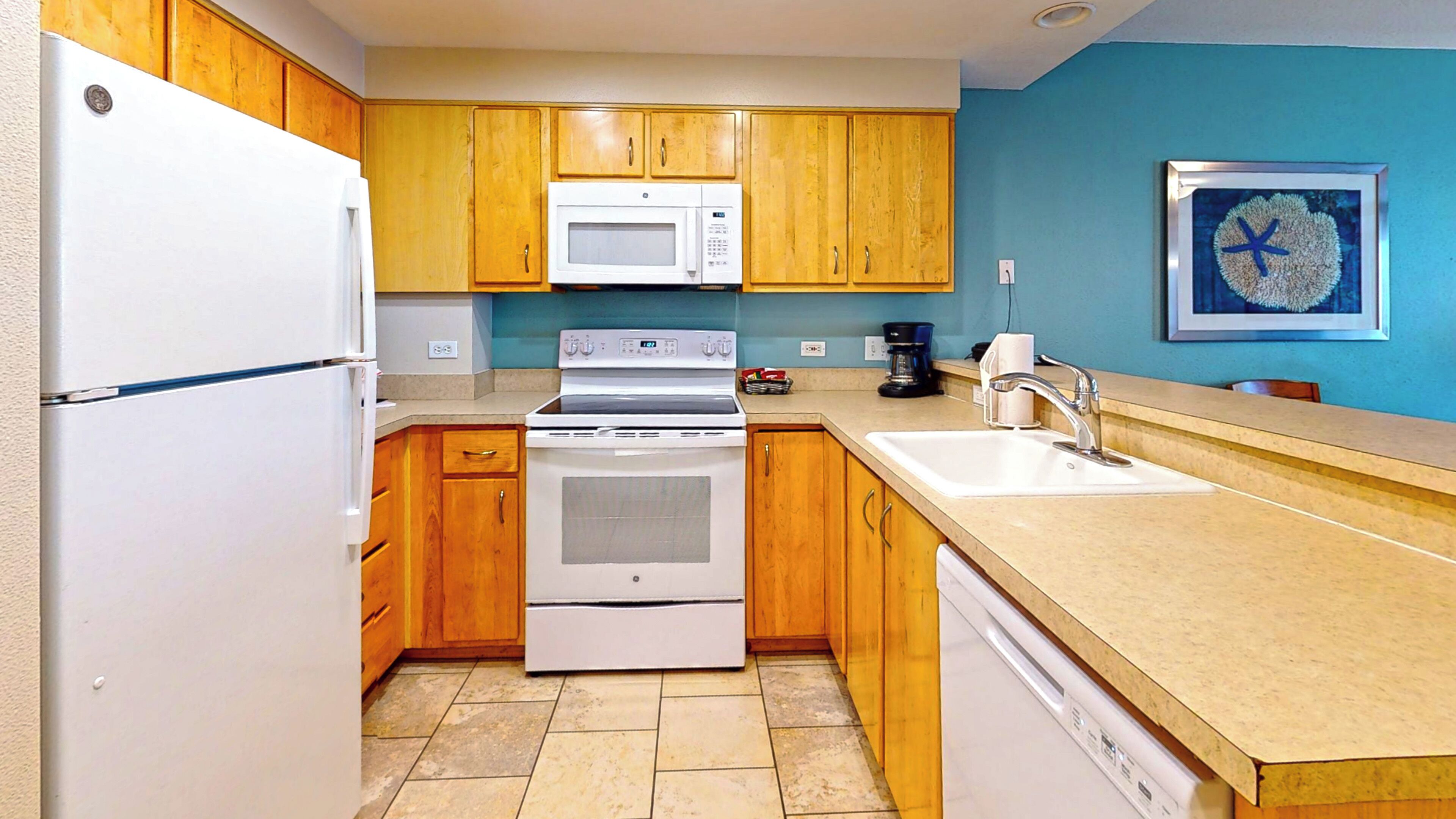 A kitchen with wooden cabinets, a white refrigerator, a microwave, an oven, a sink, and a coffee maker.