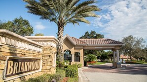 A stone wall with a sign reading "Briarwood" and a covered entrance to a building. - Fabulous 4 bedroom, 3 bath home in gate community of Briarwood (Naples)