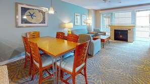 A dining area with a wooden table and chairs, a sofa, and a fireplace. - Seaside Resort - 2 Bedroom 2 Bath - Assignment 5 (Seaside)