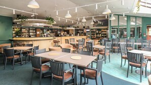 Ein Restaurant mit mehreren Tischen, Stühlen, einer Bar und Regalen voller Flaschen.