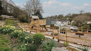 Ein Spielplatz mit Holzkonstruktionen und ein Garten mit gelben Blumen.