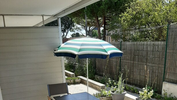 A patio with a table and chairs, a striped umbrella, and potted plants. - Studio Dans Résidence Avec Accès Direct à la Plage (Saint-Palais-sur-Mer)