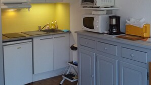 A compact kitchen with white cabinets, a microwave, a coffee maker, and a small step stool. - Studio Dans Résidence Avec Accès Direct à la Plage (Saint-Palais-sur-Mer)