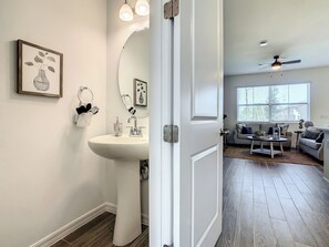 A modern bathroom with a sink, mirror, and framed artwork.