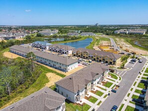 A residential area with multiple houses, a large building, and a body of water.