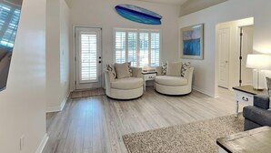 A spacious living room with a ceiling fan, two sofas, a coffee table, and a rug. - Coastal Home, Close to Beach with Pool, Golf Cart and Bikes (Miramar Beach)